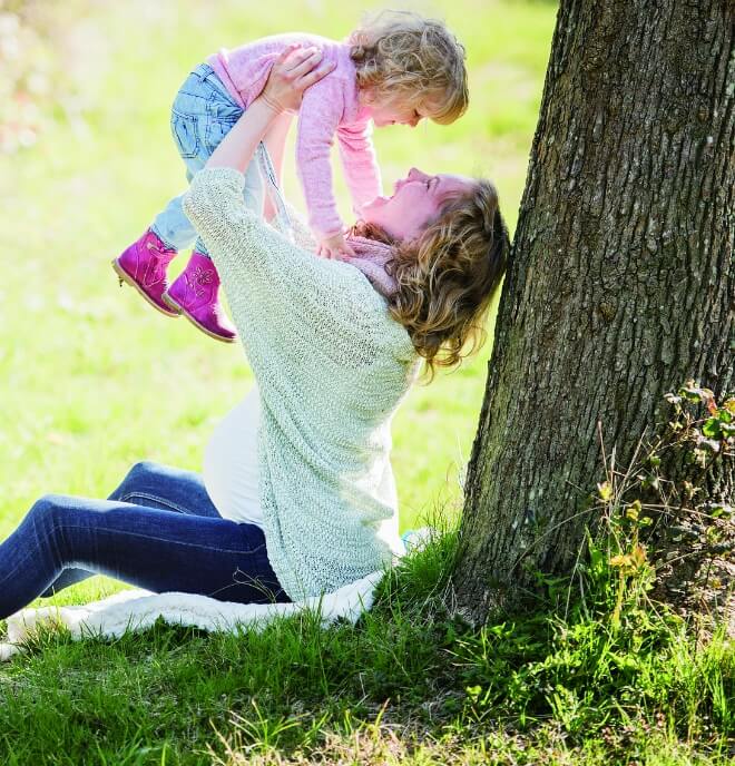 木陰で子どもを抱きかかえる女性