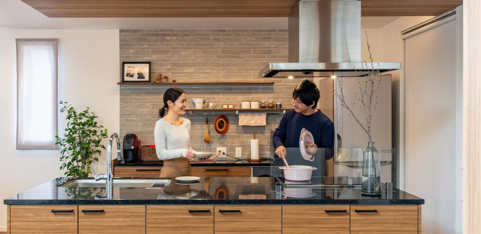 オープンキッチンで一緒に料理を楽しむ若い夫婦