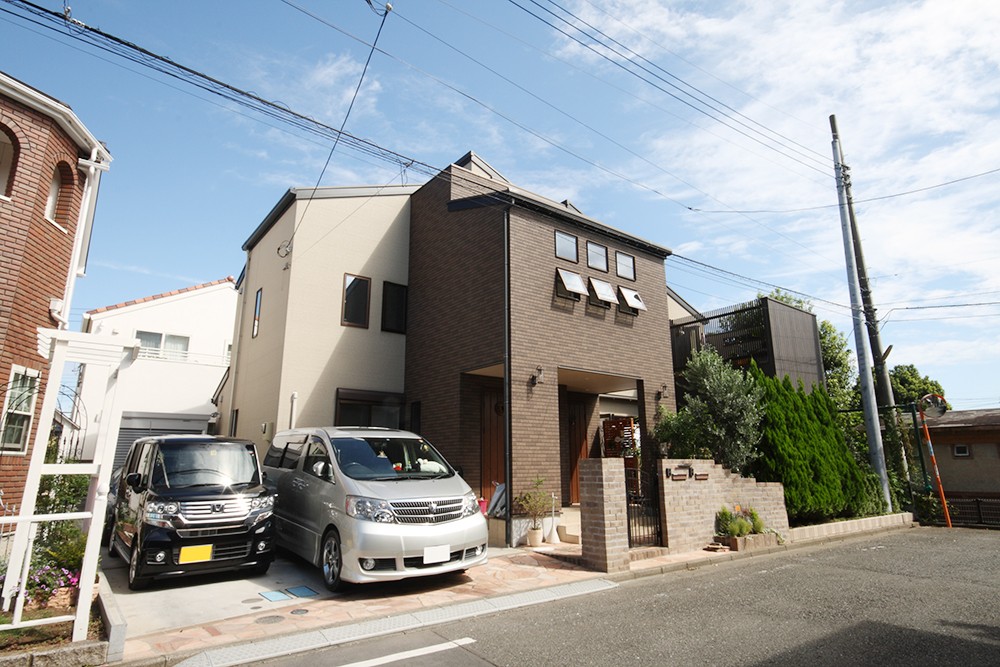 車の出入りはオープンスタイル、住まい部分はクローズドスタイルに使い分けた便利な住まいの外観