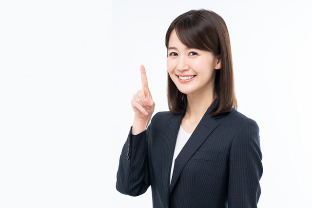 人差し指を立てるスーツ姿の女性