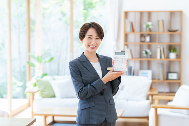 家の中で電卓を手に持つ女性