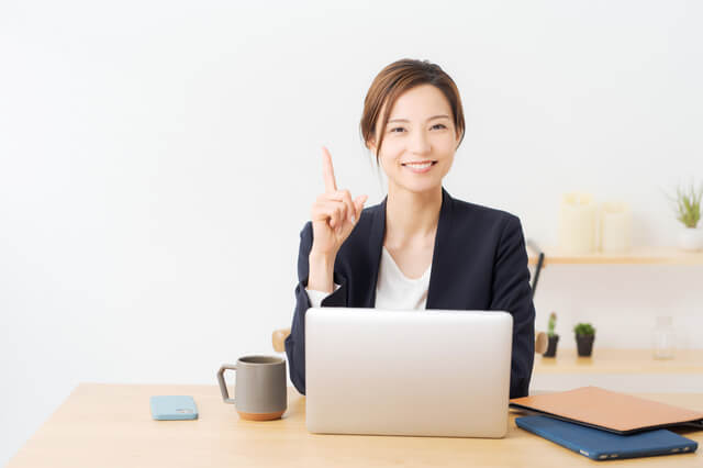 指を立てる女性とパソコン