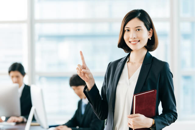 指を立てるスーツ姿の女性