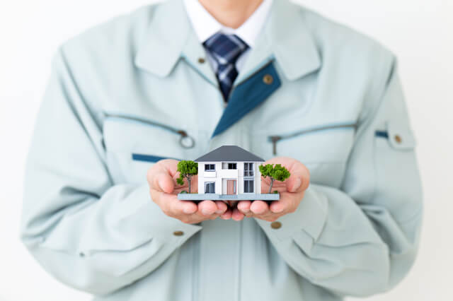 家の模型を手に持つハウスメーカーの人